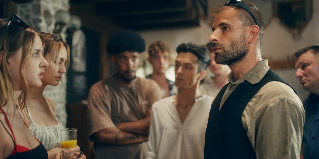 Gruppe steht vor Polizist. Trailerausschnitt aus RTL+ Serie "Villa der Liebe"